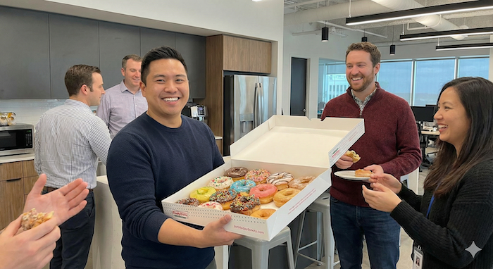 Birthday person treating colleagues to donuts. / 同僚にドーナツを配る誕生日主役。